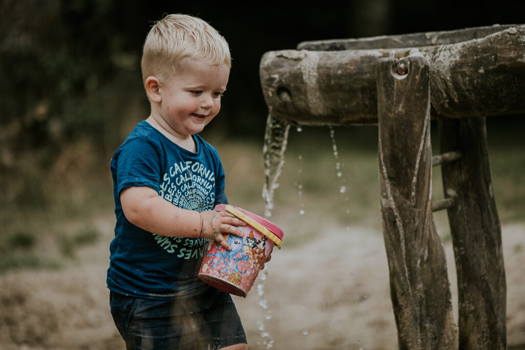 Fotoshoot Friesland. Kindje vult zijn emmertje met water bij de waterspeelplaats. Fotoreportage door fotograaf Nickie Fotografie uit Dokkum.