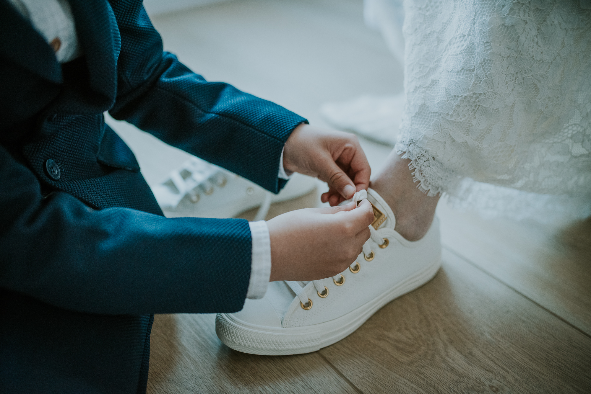 De voorbereidingen van de bruid. Zoontje strikt de veters van de sneakers. Trouwreportage door trouwfotograaf Nickie Fotografie uit Dokkum, Friesland.