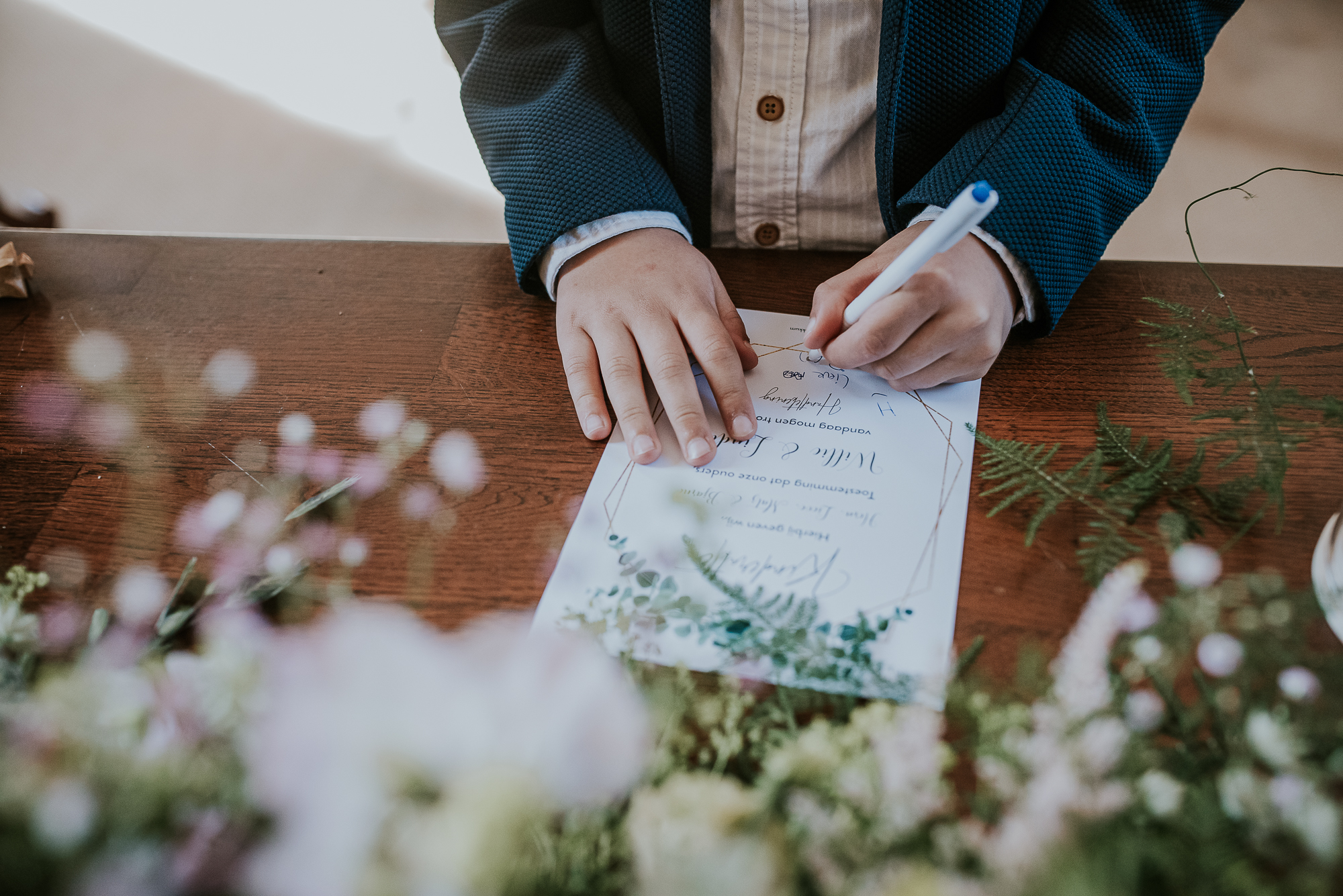 Het ondertekenen van de kinderakte tijdens de kerkelijke cermonie op de bruiloft. Huwelijksreportage door huwelijksfotograaf Nickie Fotografie uit Dokkum.
