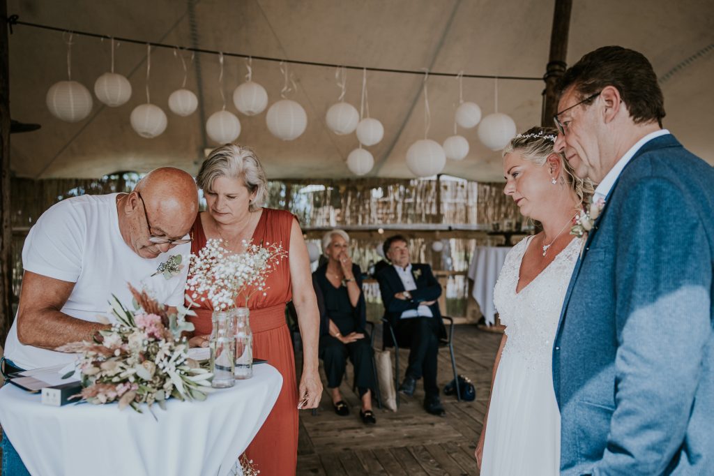 De getuigen zetten hun handtekening op de trouwakte.  Bruidsfotografie door bruidsfotograaf Nickie fotografie uit Dokkum, Friesland.