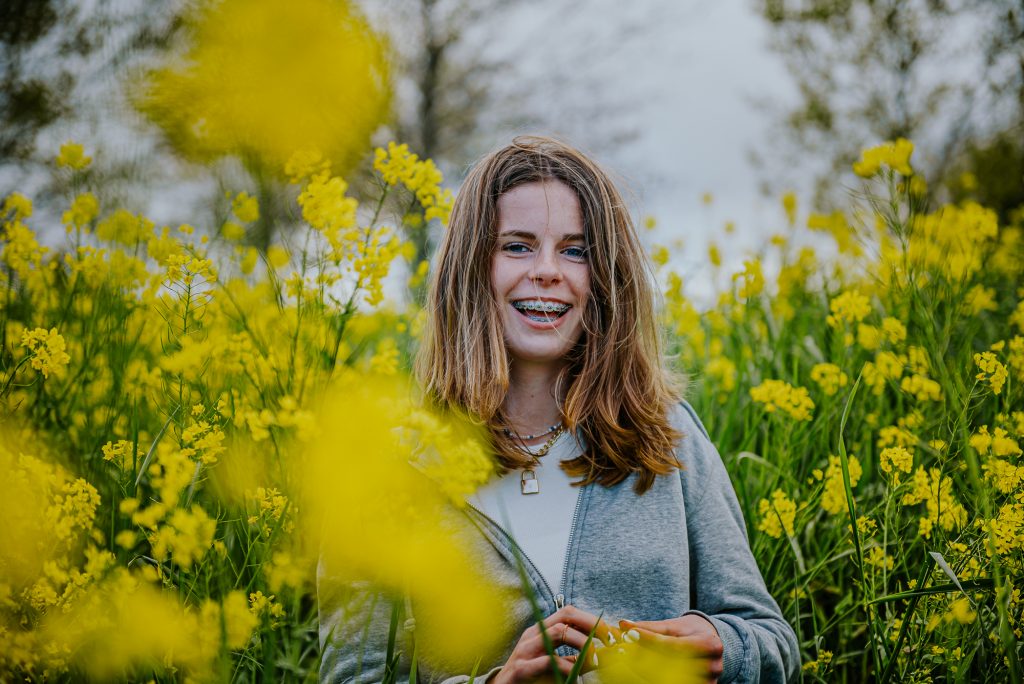 Vrolijke meisje in geel bloemenveld. Portretfotografie door portretfotograaf Nickie Fotografie uit Dokkum, Friesland