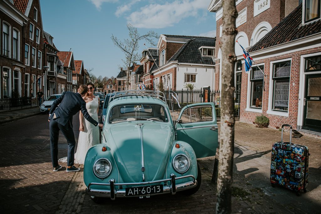 Bruidspaar vertrekt in prachtige trouwauto, een oude Kever. Fotoreportage door fotograaf NIckie Fotografie uit Dokkum, Friesland.