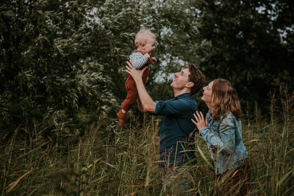 Speels portret van ouders met baby in de natuur door fotograaf NIckie Fotografie uit Dokkum, Friesland.