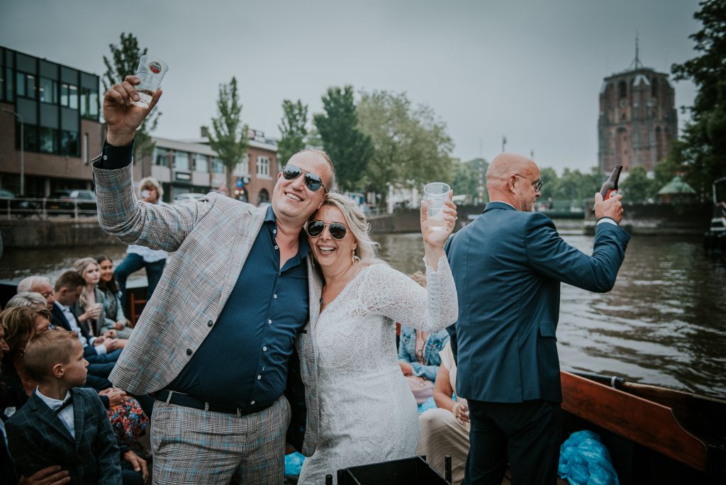 Het bruidspaar op de boot met in de achtergrond de scheve toren de Oldehove in Leeuwarden. Huwelijksreportage door huwelijksfotograaf Nickie Fotografie uit Dokkum, Friesland