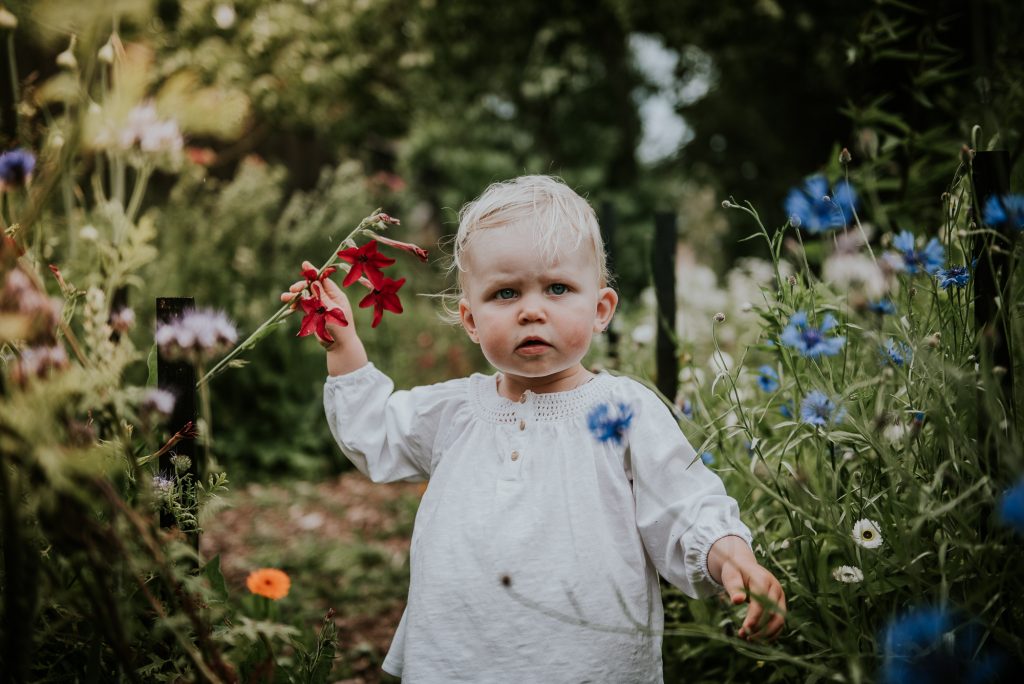 Klein meisje onder de indruk van de prachtige bloementuin. Kinderportret door portretfotograaf Nickie Fotografie uit Dokkum, Friesland