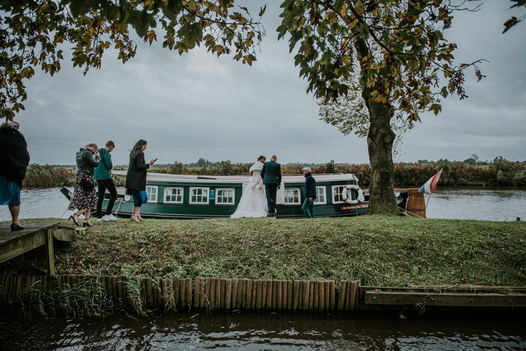 Bruidspaar vaart met de trekschuit naar de trouwzaal in het oude stadshuis. Bruidsreportage door bruidsfotograaf Nickie Fotografie uit Friesland.