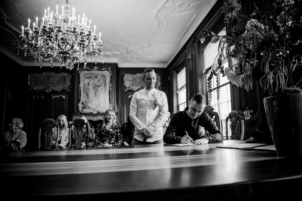 Getuige ondertekent de trouwakte in de trouwzaal van Dokkum. Trouwreportage door trouwfotograaf NIckie Fotografie uit Friesland.