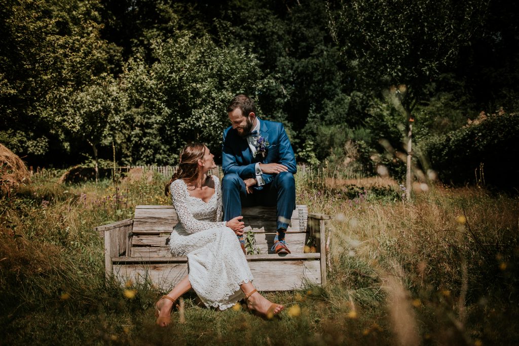 Bruid en bruidegom op houten bankje in de natuur. Trouwfotografie in Groningen door trouwfotografe Nickie Fotografie uit Dokkum, Friesland.