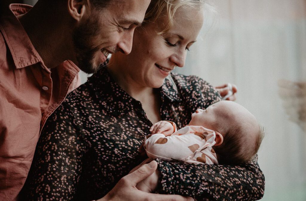 Newborn fotoshoot Friesland, Drachten, door fotograaf Nickie Fotografie. Vader en moeder bewonderen hun pasgeboren dochter.
