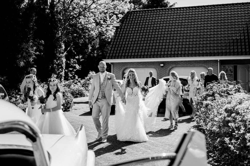 Trouwen in Friesland. Bruidspaar loopt naar de trouwauto. Huwelijksfotografie door huwelijksfotograaf Nickie Fotografie uit Dokkum.