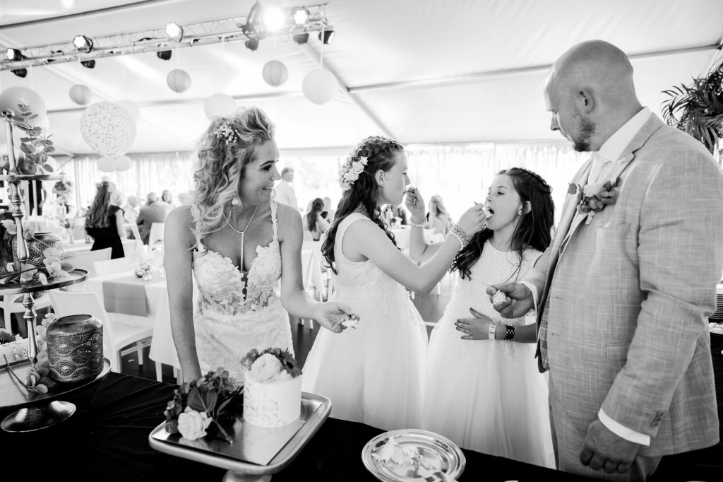 Het aansnijden van de bruidstaart. Fotograaf Friesland, Nickie Fotografie. De bruidsmeisjes nemen het eerste hapje van de trouwtaart.