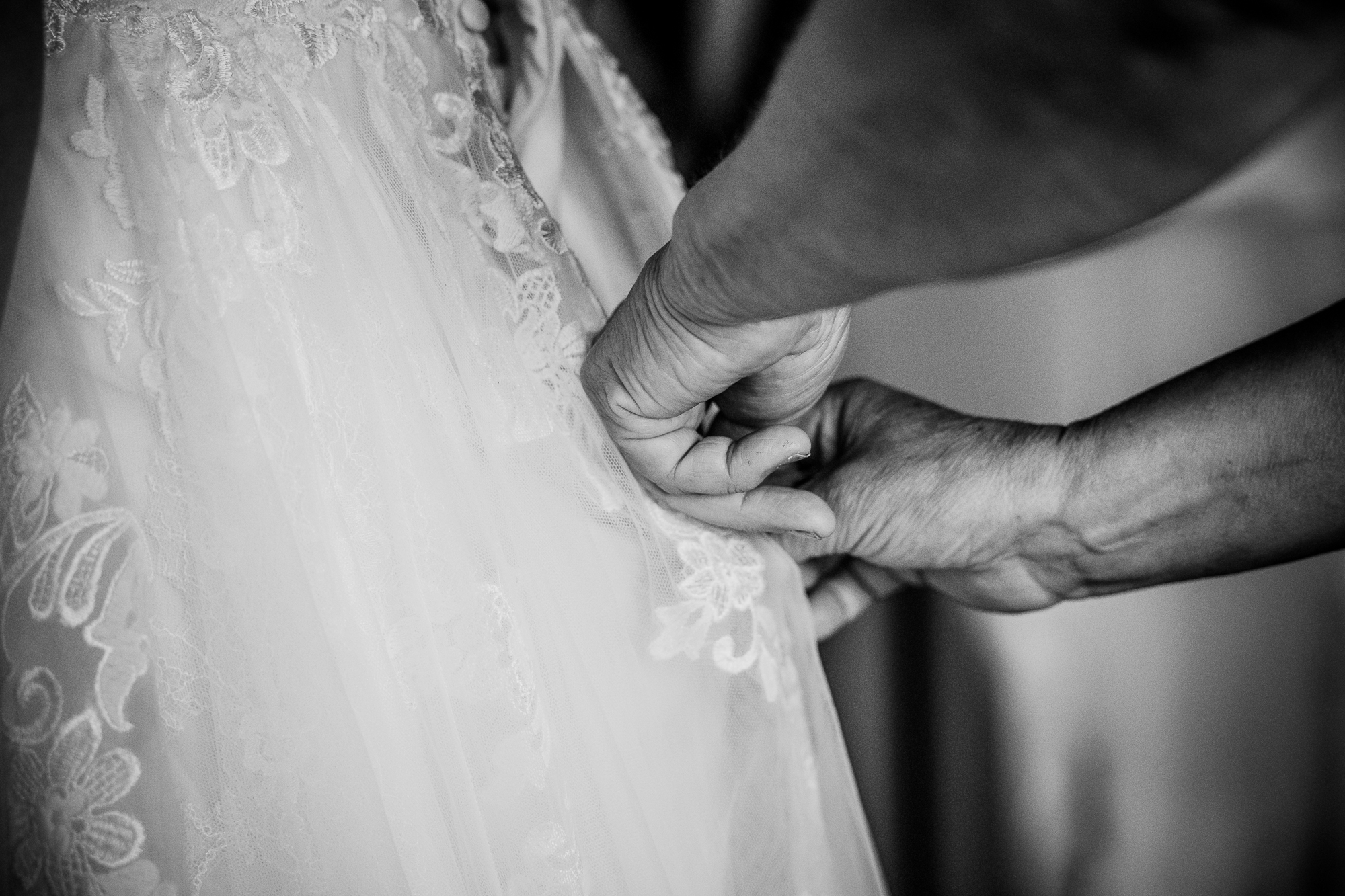 Zwartwit huwelijksreportage door huwelijksfotograaf Nickie Fotografie uit Friesland. Moeder helpt bij het aankleden van de bruid.