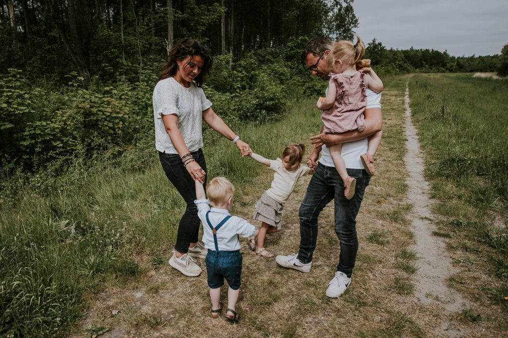 Lifestyle gezinsshoot door fotograaf Nickie Fotografie. Ouders en hun kinderen spelen Jan Huigen in de ton.