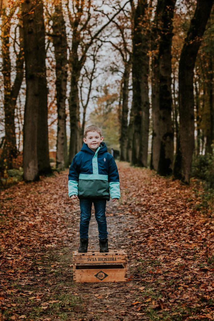 Herfst kindershoot Friesland door fotograaf Nickie Fotografie. Kleuter staat op een houten kistje in het Driesumerbos.