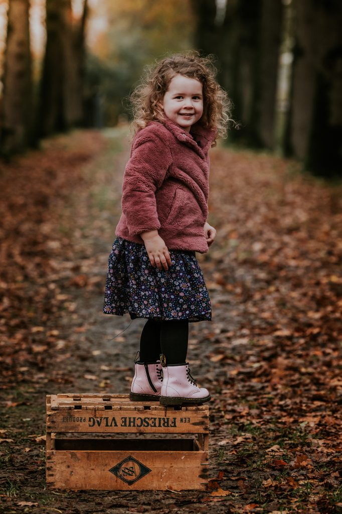 Kinderfotografie Friesland door fotograaf Nickie Fotografie. Peuter staat op een oude houten kistje in het bos.