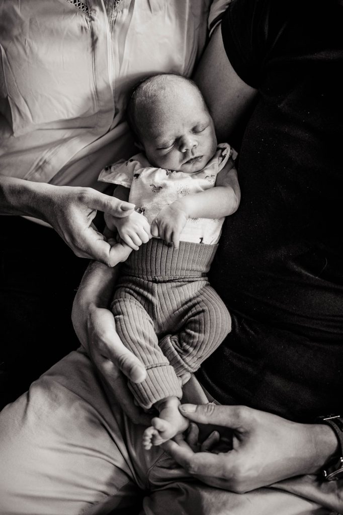 Newbornfotograaf Friesland, Nickie Fotografie uit Dokkum. Baby ligt te slapen bij papa op schoot.