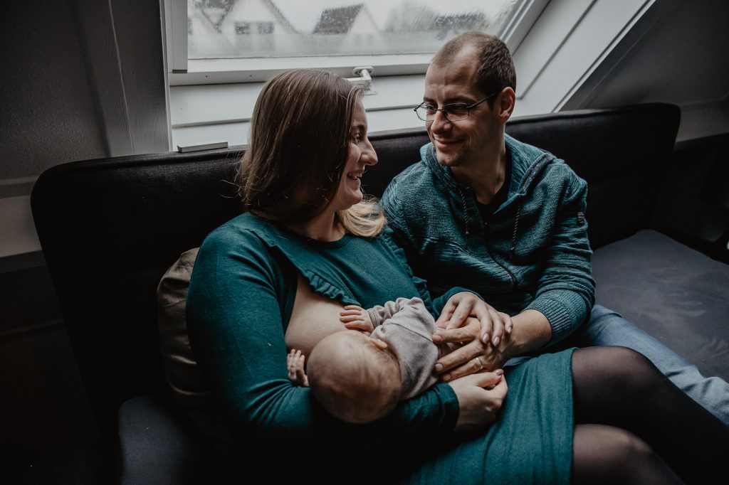 Lifestyle babyshoot Friesland, Kollum, door newbornfotograaf Nickie Fotografie. Gezinsportret terwijl de moeder borstvoeding geeft.