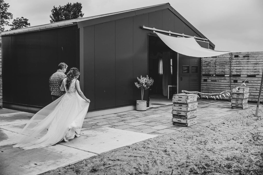 Bruid wordt weggegeven door haar vader voor de bruiloft in de stal. Huwelijksfotografie door trouwfotograaf Nickie Fotografie.