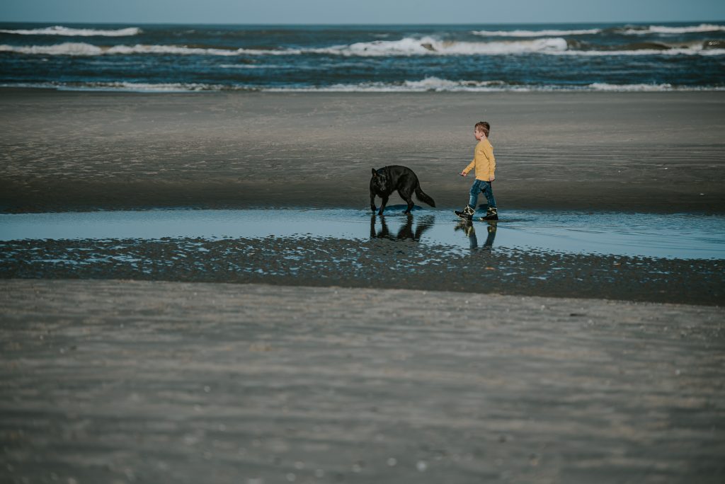 Fotoshoot Ameland, Friesland, door fotograaf NIckie Fotografefie. Jongen laat hond uit op het strand.