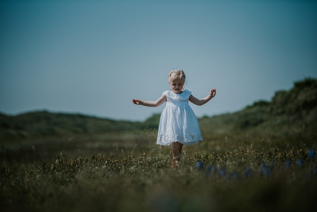 Portret van klein meisje in wit jurkje in de duinen, door portretfotograaf Nickie Fotografie uit Dokkum, Friesland