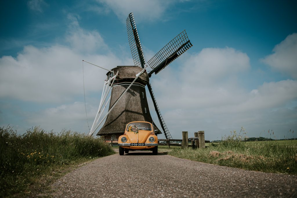 Bruidsshoot bij de molen van Hantum met oranje Kever als gave trouwauto. Trouwfotografie door trouwfotograaf Nickie Fotografie uit Dokkum, Friesland