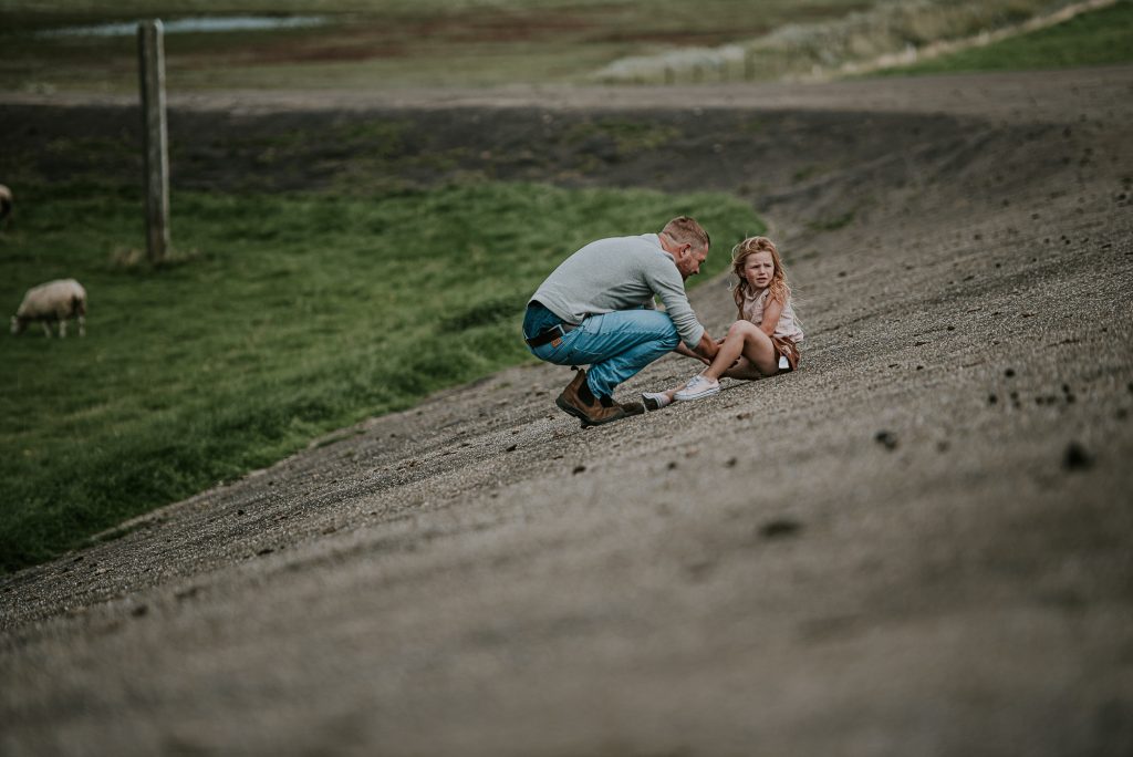 Vader is zijn dochter aan het troosten na het vallen. Gezinsfotografie Friesland door fotograaf Nickie Fotografie uit Dokkum.