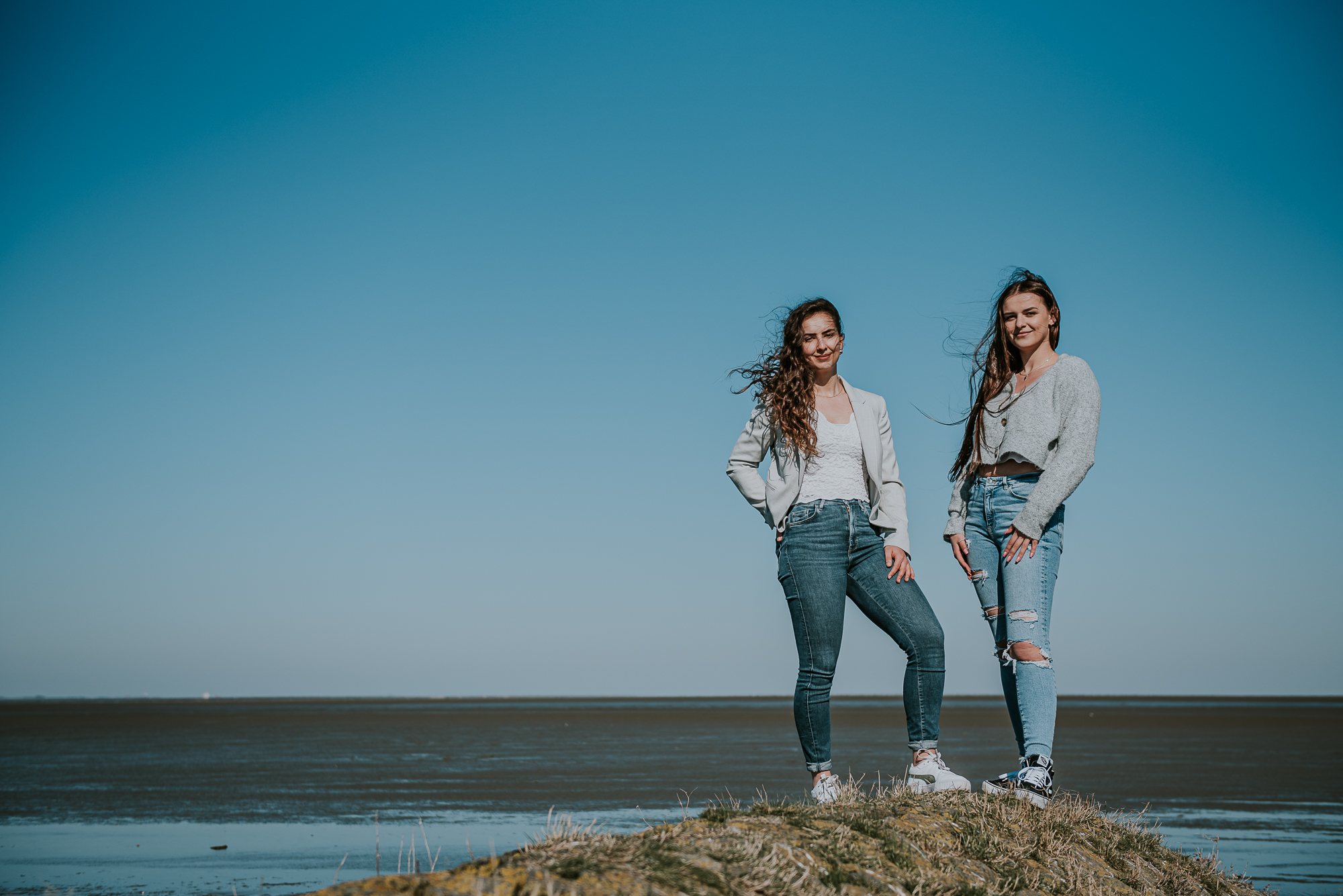 Fotoshoot bij de Waddenzee, Peasens-Moddergat, door fotograaf NIckie Fotografie uit Friesland. Portret van twee zussen bij de Waddenzee door portretfotograaf Nickie Fotografie.