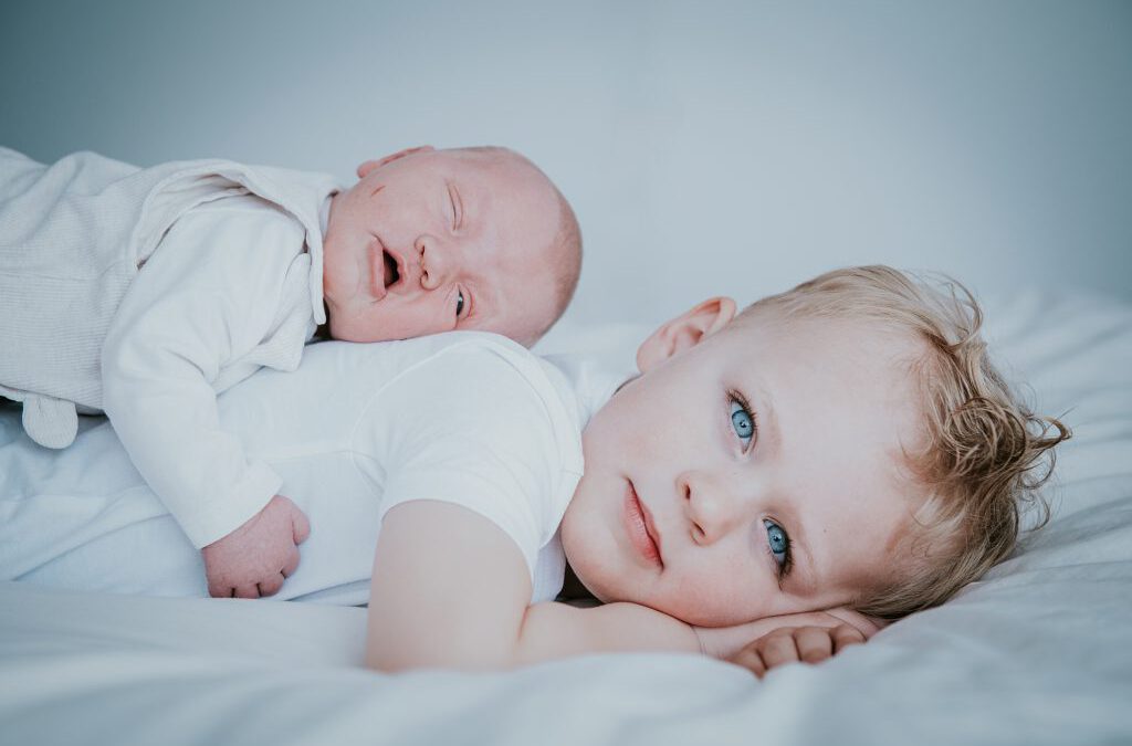 Newbornshoot met grote broer door fotograaf Nickie Fotografie uit Dokkum, Friesland. Baby ligt op de rug van haar broer.