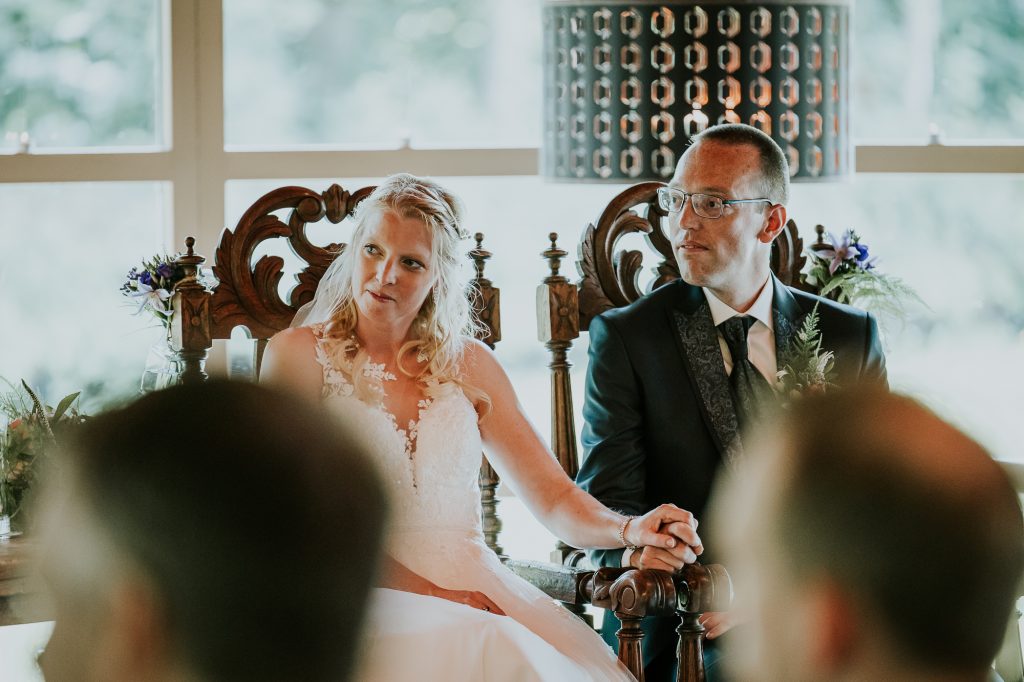 Het bruidspaar aandachtig aan het luisteren tijdens de huwelijksceremonie. Trouwerijreportage door trouwerijfotograaf Nickie Fotografie uit Friesland.