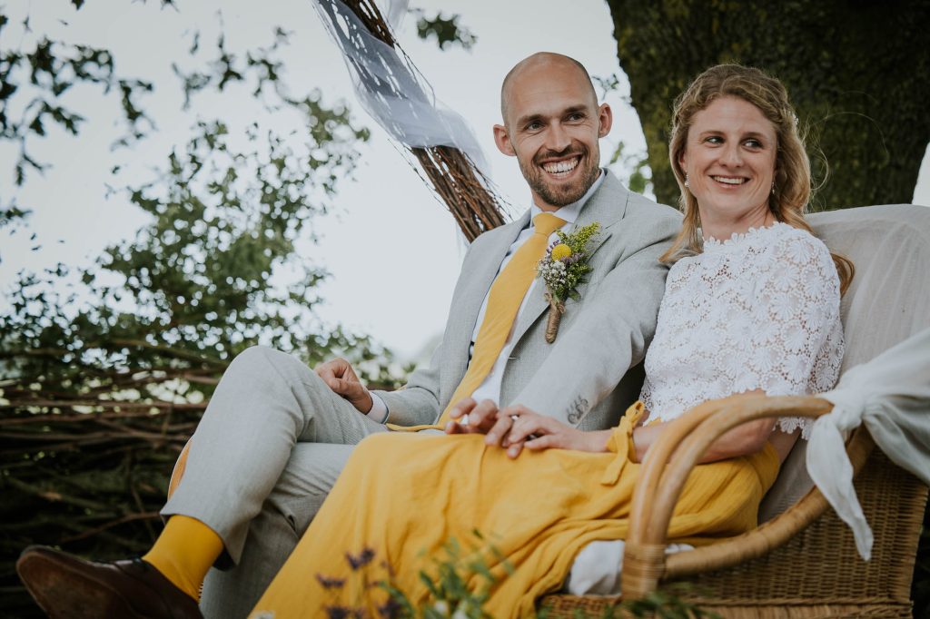 Buiten trouwen in Friesland. Het bruidspaar in het geel tijdens de trouwceremonie. Huwelijksfotografie door fotograaf Nickie Fotografie.