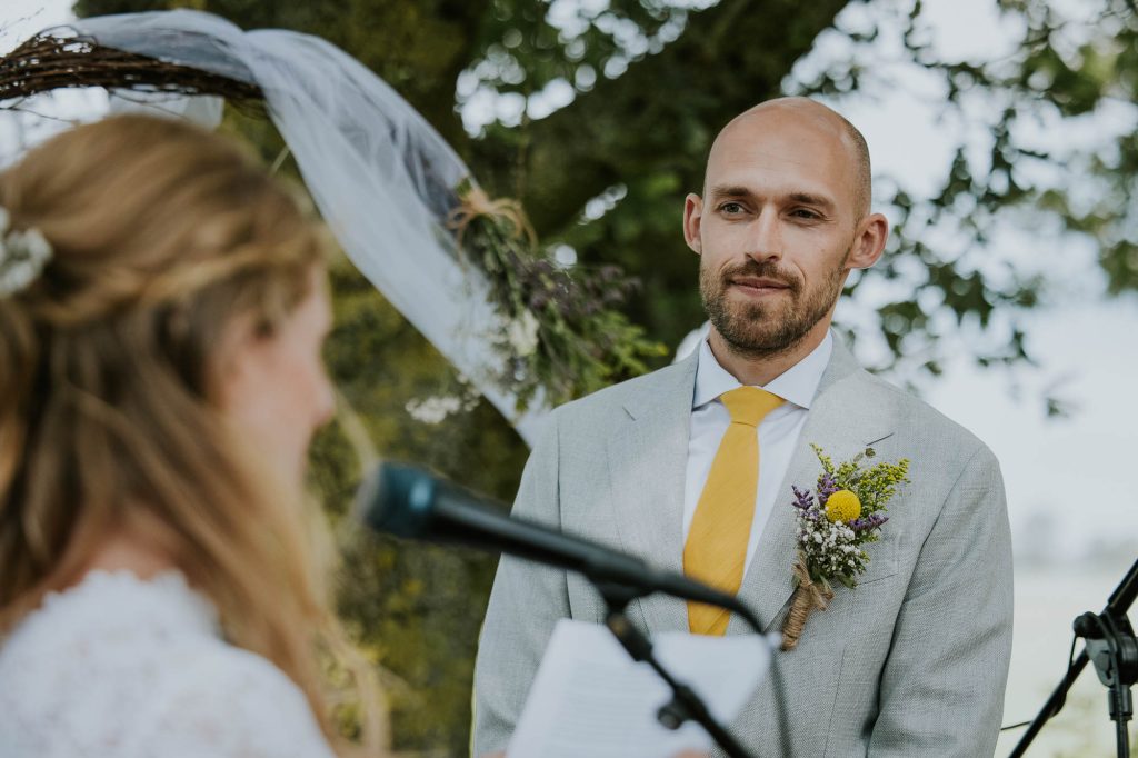 Het voorlezen van de trouwgeloftes tijdens de buiten bruiloft. Trouwfotografie door huwelijksfotograaf Nickie Fotografie uit Dokkum, Friesland
