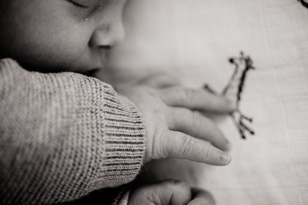 Babyshoot, een zwart-wit close-up detail foto van een schattig babyhandje door babyfotograaf Nickie Fotogafie uit Dokkum, Friesland.