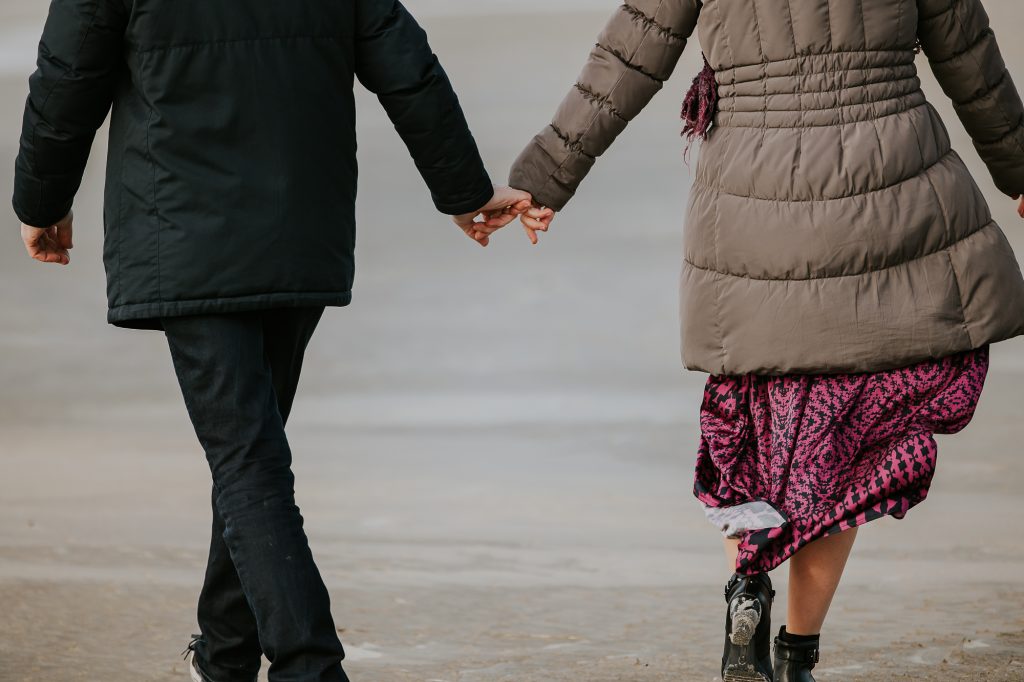 Hand in hand wandelen wij over het strand. Fotoshoot door fotograaf Nickie Fotografie uit Dokkum.