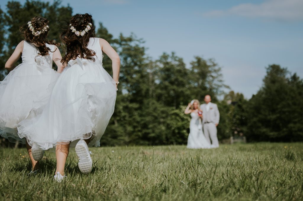 De bruidsmeisjes rennen naar het bruidspaar toe. Huwelijksreportage door trouwfotograaf NIckie Fotografie.