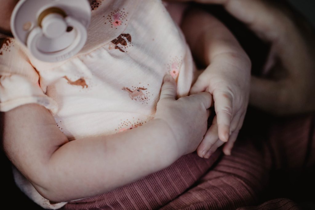 Babyfotografie Burgum door fotograaf Nickie Fotografie. Baby houdt haar eigen handje vast.