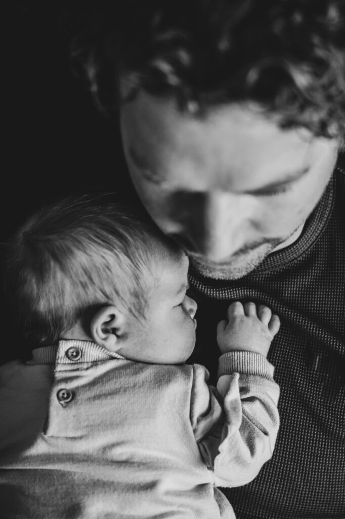 Zwartwit babyfotografie. Portret van vader met zijn pasgeboren dochtertje door newbornfotograaf Nickie Fotografie uit Dokkum, Friesland.