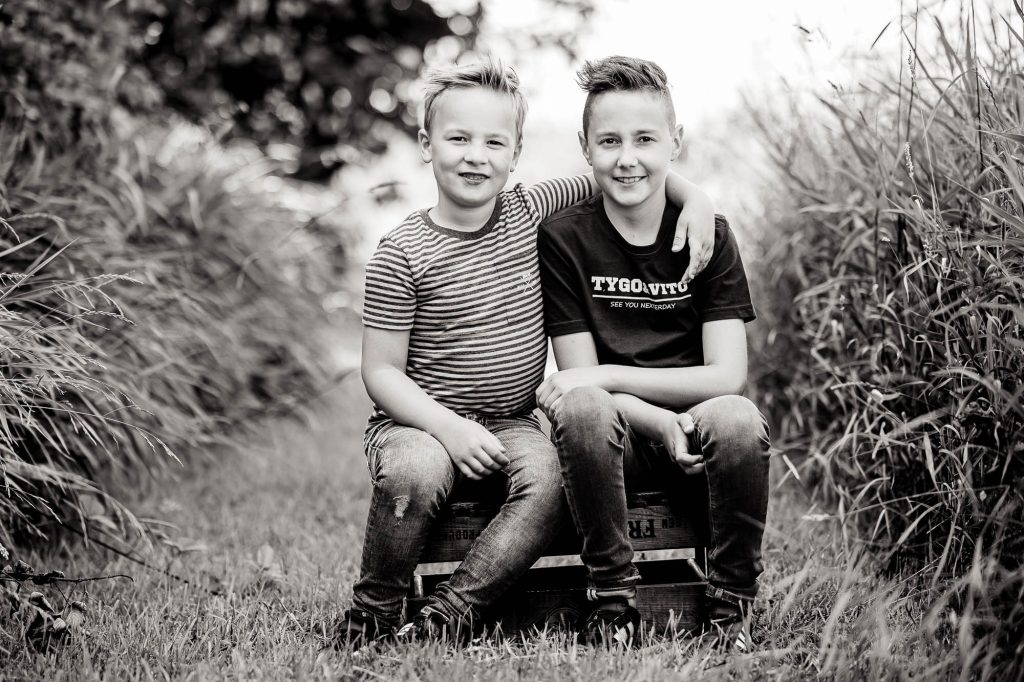 Fotoshoot Friesland door fotograaf Nickie Fotografie. Zwartwit portret van twee broertjes op een oude houten aardappelkistje in Rinsmapole.