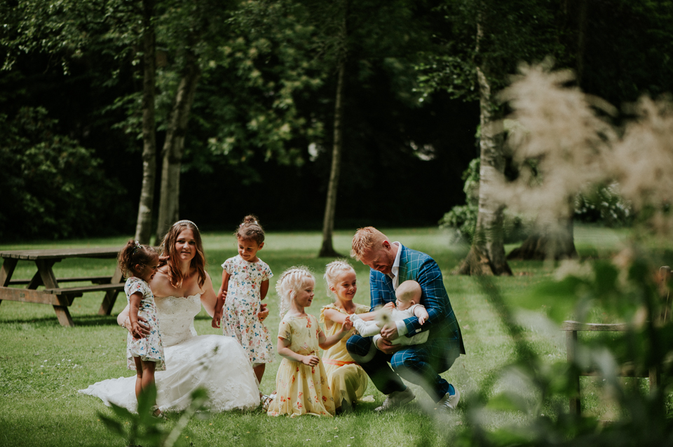 Bruidspaar met alle bruidskindjes in kloostertuin van Karmelklooster Drachten. Huwelijksfotograaf Nickie Fotografie.
