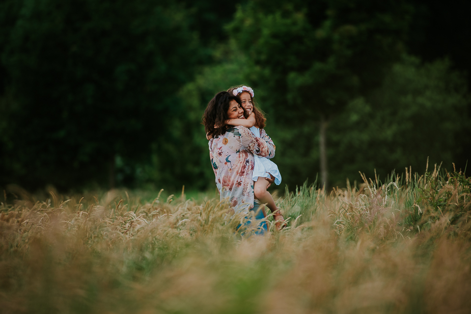 Fotoshoot Friesland. Portret van moeder en jongste dochter 
 in het hoge gras tijdens de fotosessie. Door fotograaf Nickie Fotografie.