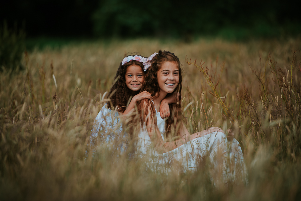 Portret van zusjes in het hoge gras door portret fotograaf Nickie Fotografie uit Dokkum, friesland
