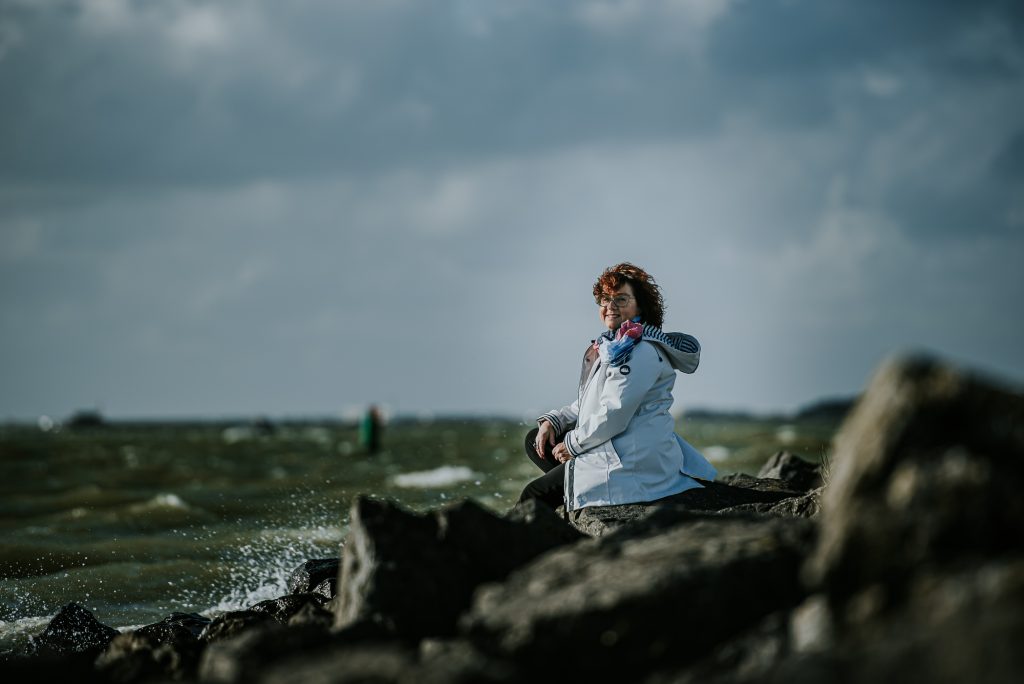 Zittend aan het IJsselmeer uitkijkend over de ruige golven. Portret door portretfotograaf Nickie Fotografie