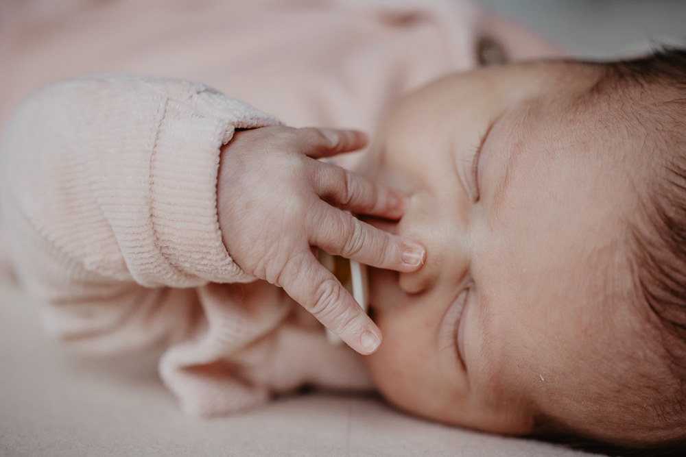Newbornshoot Heerenveen door fotograaf Nickie Fotografie uit Friesland. Baby probeert haar speen te pakken.