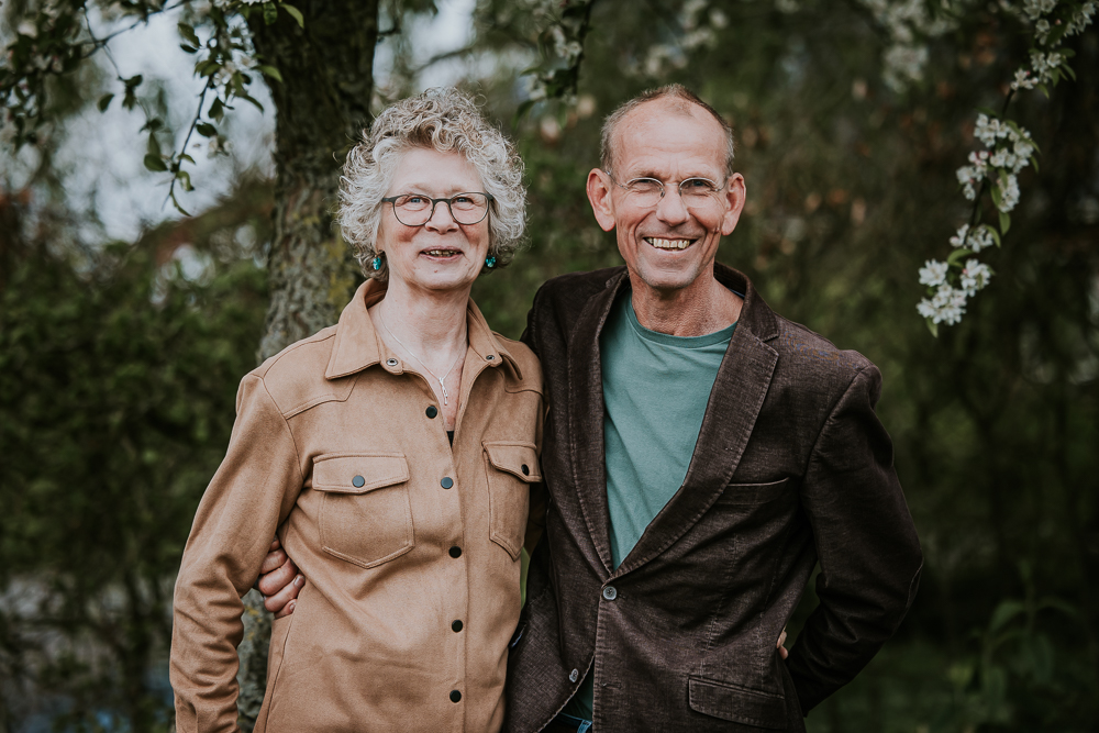Portret van de ouders in de tuin bij de bloeiende appelboom. Fotoshoot door fotograaf Nickie Fotografie uit Friesland.