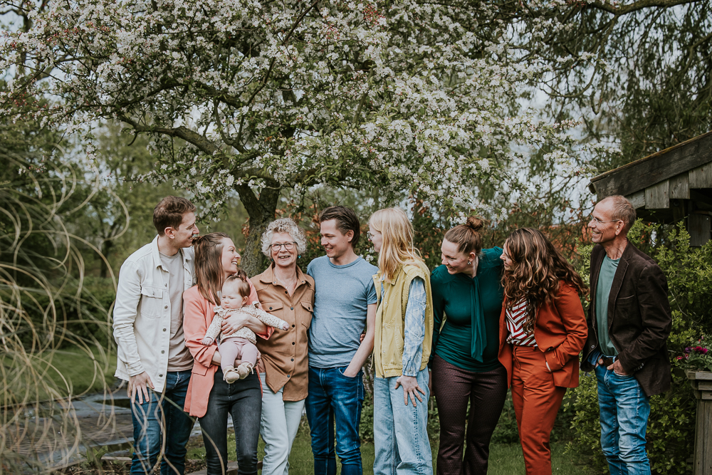Familieportret in de achtertuin, bij bloeiende appelboom, door fotograaf Nickie Fotografie uit Friesland.