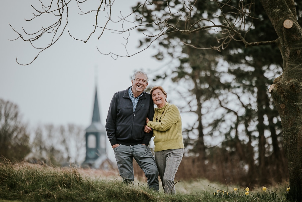 Fotograaf Schiermonnikoog. Koppelshoot van ouder echtpaar in de duinen met op de achtergrond een kerktoren. Shoot Zuidertoren Schiermonnikoog