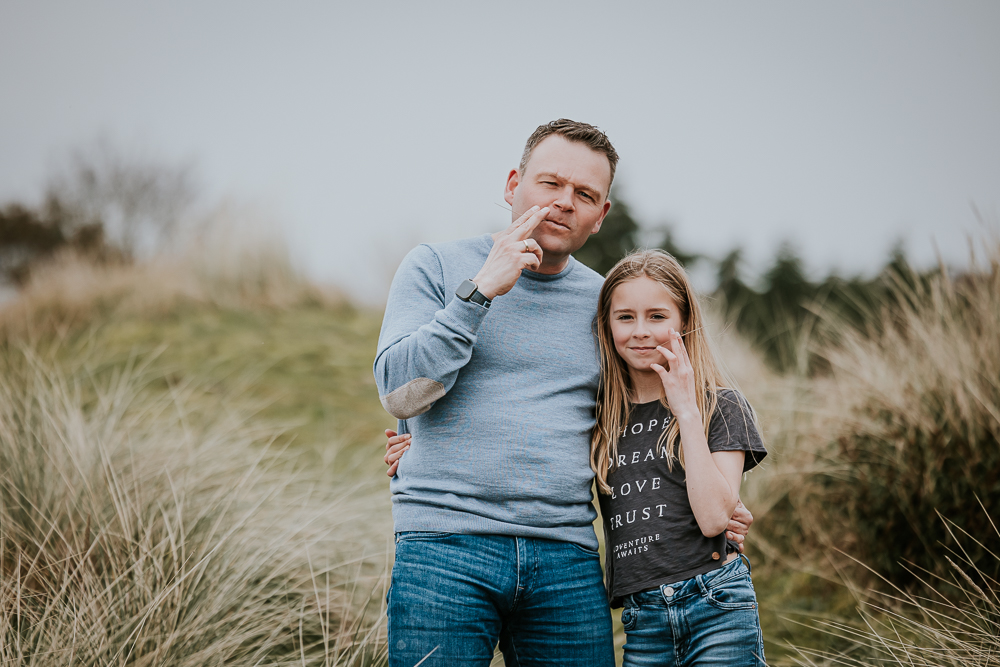 Fotoshoot Schiermonnikoog door fotograaf Nickie Fotografie. Portret van vader en dochter die doen alsof ze riet aan het roken zijn.