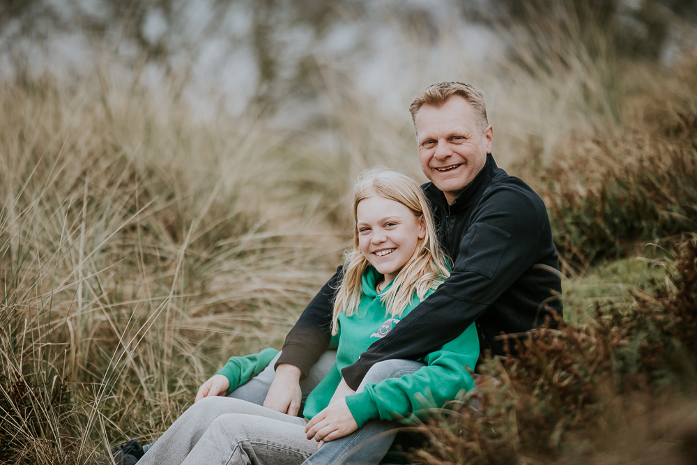 Fotoshoot Schiermonnikoog. Portret van vader en dochter zittend in de duinen door Nickie Fotografie.