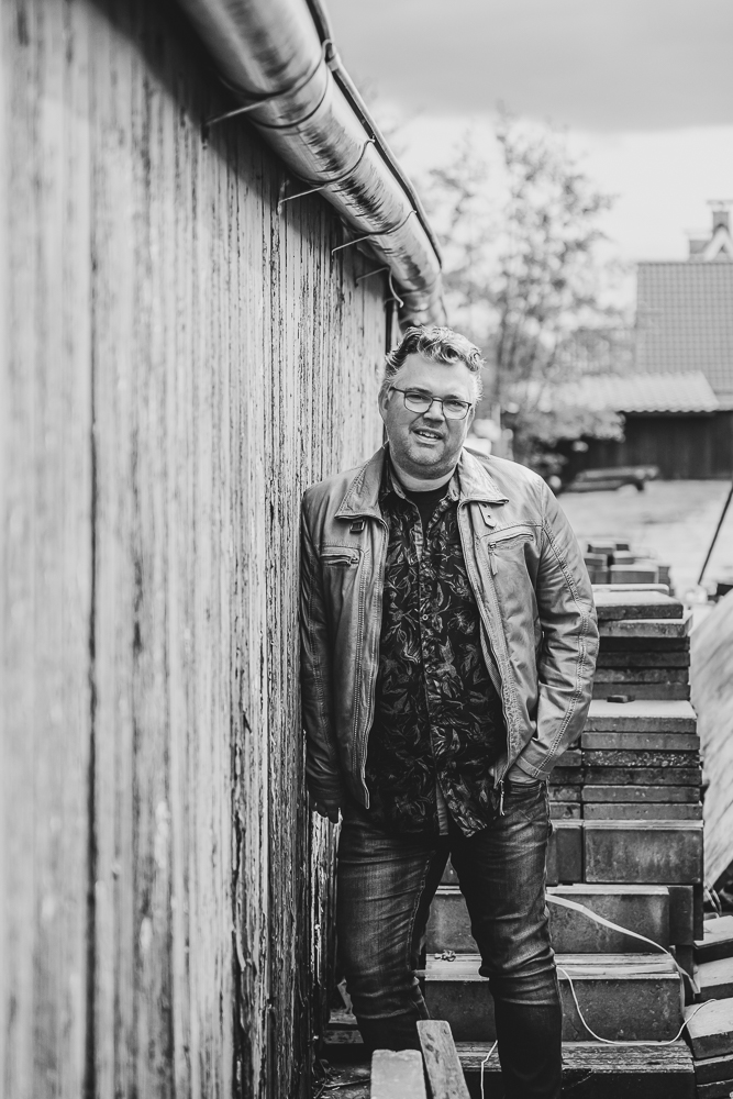 Zwartwit portret van vader leunend tegen de oude houten muur door fotograaf Nickie Fotografie uit Friesland.