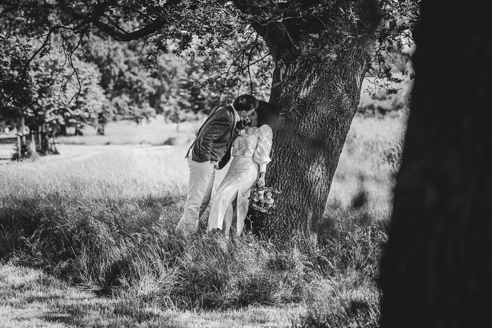 Trouwreportage in het park Wetter en wille te Burgum. Bruidspaar kust elkaar onder de boom. Zwartwit trouwreportage door bruidsfotograaf Nickie Fotografie uit Friesland.