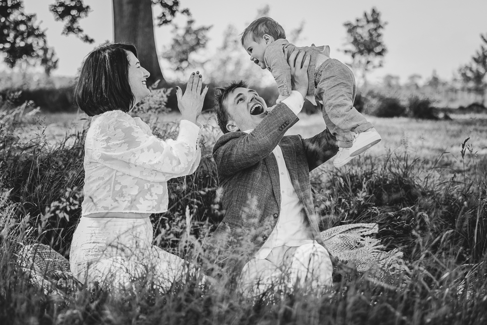 Bruidsfotograaf Friesland. Zwart-wit trouwreportage in Burgum. Spelende gezinsfoto van het bruidspaar met hun zoontje door Nickie Fotografie.